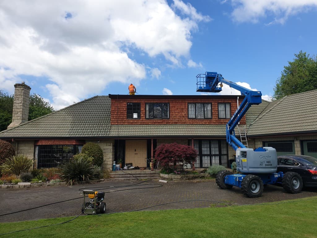 Roof cleaning with boom lift and pressure washing on a residential property